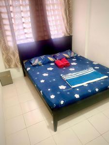 uma cama com um edredão azul com flores em Mk guesthouse em Kuantan