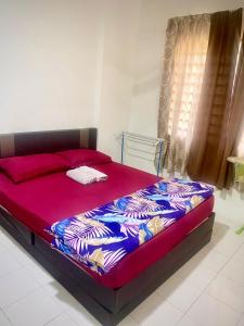 uma cama num quarto com um cobertor vermelho e azul em Mk guesthouse em Kuantan