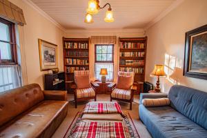 a living room with a couch and chairs and bookshelves at Crossroads Cottage in Dullstroom