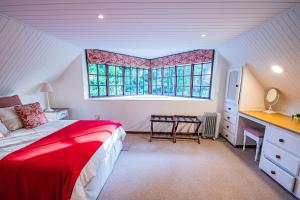 a bedroom with a red bed and a window at Crossroads Cottage in Dullstroom