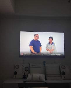 uma televisão de ecrã plano numa parede acima de uma cama em Saint Honore Executive 1 Full bed, 1 Sofa bed 1 Pull out bed 2BR em Iloilo City