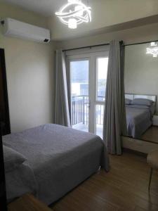 a bedroom with a bed and a large window at Saint Honore Executive 1 Full bed, 1 Sofa bed 1 Pull out bed 2BR in Iloilo City