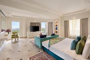 Aurika, Mumbai Skycity - Luxury by Lemon Tree Hotels في مومباي: غرفة نوم بسرير كبير وغرفة معيشة