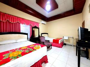 a hotel room with two beds and a television at Hotel Dirgahayu Ponorogo in Ponorogo