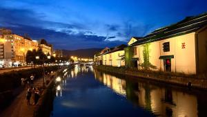 a group of people walking along a river at night at Ryoan / Vacation STAY 80251 in Otaru