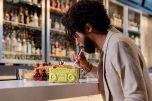 a man sitting at a bar drinking from a straw at Aloft Me'aisam, Dubai in Dubai