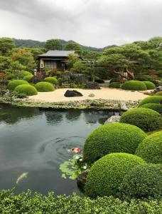 un estanque en un jardín con una casa al fondo en 吉吉の家, en Tokio