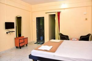 a bedroom with a bed and a desk and a tv at Comforts Stays Kihim in Kīhīm