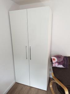 une armoire blanche dans une pièce avec une chaise dans l'établissement Bietigheimer Hideaway - Modern und Gemütlich, à Bietigheim