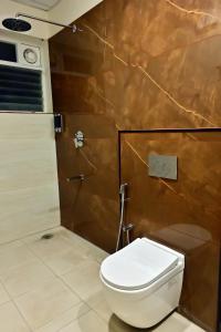 La salle de bains est pourvue de toilettes et d'un mur marron. dans l'établissement The Mallika Sapphire, à Chikmagalur