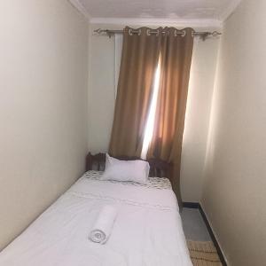 a bed in a small room with a window at consortium apartments in Bungoma