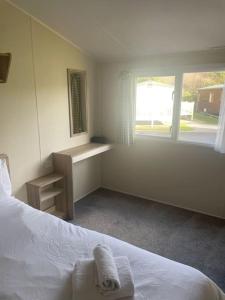 ein weißes Schlafzimmer mit einem Bett und einem Fenster in der Unterkunft Delightful two bedroom caravan on Par Beach. in Par