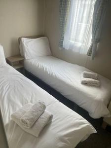 2 Betten in einem Zimmer mit Handtüchern darauf in der Unterkunft Delightful two bedroom caravan on Par Beach. in Par