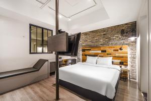 a bedroom with a white bed and a brick wall at Hotel Yaja Siheung Jeongwang Branch in Siheung