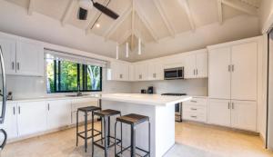 a kitchen with white cabinets and a large island with stools at Gorgeous Four Bedroom Villa in Cajuiles