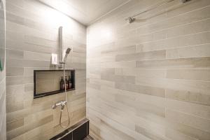 a bathroom with a shower with a tile wall at Hotel Yaja Siheung Jeongwang Branch in Siheung