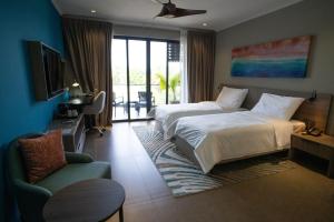 a hotel room with two beds and a chair at Thalassa Seychelles in Beau Vallon