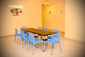 a dining room with a wooden table and blue chairs at Queen's Residency in Guwahati