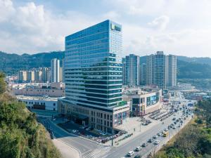 ein hohes Glasgebäude in einer Stadt mit Autobahn in der Unterkunft Holiday Inn Express Bazhong Center, an IHG Hotel in Bazhong