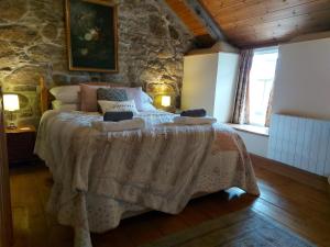 ein Schlafzimmer mit einem großen Bett in einer Steinmauer in der Unterkunft Kitts Cottage Rural, Woodburner, King Size Bed in Redruth