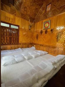 1 cama blanca grande en una habitación con paredes de madera. en The Memory villa, en Mộc Châu