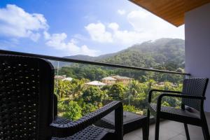a balcony with two chairs and a view of a mountain at Thalassa Seychelles in Beau Vallon