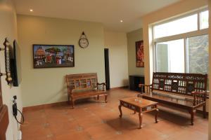 a living room with benches and a clock on the wall at Ponni Homestay Kumbakonam in Kumbakonam