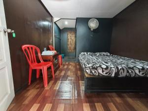 a bedroom with a bed and a table and a chair at Maznah Guest House in Cherating
