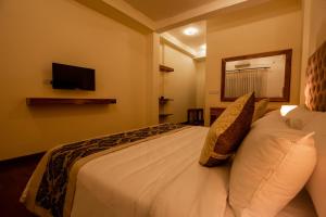 um quarto com uma grande cama branca e uma televisão na parede em Manthra Leisure em Kandy