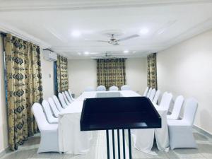 una sala de conferencias con mesa y sillas blancas en HILLS HAVEN HOTEL, en Accra