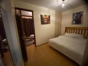 Schlafzimmer mit einem weißen Bett und einem Spiegel in der Unterkunft Havana Apartments-South B in Nairobi