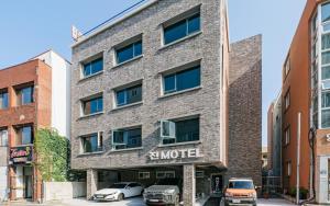 un edificio de ladrillo con coches estacionados frente a él en Jin Motel en Seogwipo