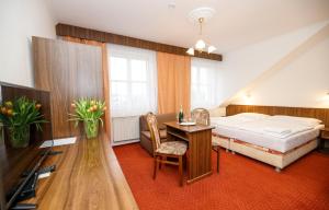 a bedroom with a bed and a desk and a table at Penzion Pomnenka in Luhačovice