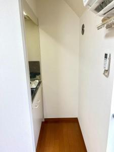 a small kitchen with white walls and a wooden floor at Shinjuku sanchome Hana House in Tokyo