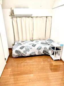 a bed with a curtain in a room with a wooden floor at Shinjuku sanchome Hana House in Tokyo