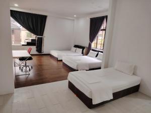 a hotel room with two beds and a desk at Mersing Maple Villa in Mersing