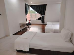 a bedroom with two beds and a desk and a window at Mersing Maple Villa in Mersing