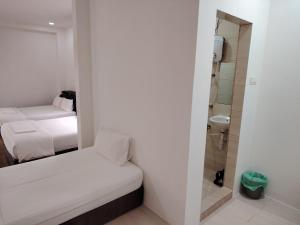 a small room with two beds and a bathroom at Mersing Maple Villa in Mersing