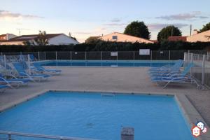 ein großer Pool mit blauen Stühlen und einem Zaun in der Unterkunft Maison en résidence avec piscine in Le Château-dʼOléron