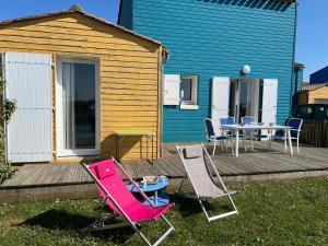 2 Stühle und ein Tisch auf einer Terrasse mit einem Haus in der Unterkunft Maison en résidence avec piscine in Le Château-dʼOléron