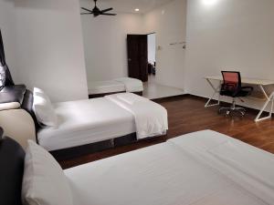 a hotel room with two beds and a desk at Mersing Maple Villa in Mersing