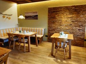 a restaurant with wooden tables and chairs and a brick wall at Hotel Bergblick in Scheidegg