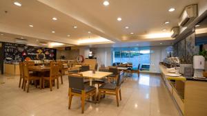 a restaurant with wooden tables and chairs and a cafeteria at Metland Hotel Cirebon by Horison in Cirebon