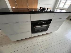 cocina con armarios blancos y encimera negra en Central Helsinki Punavuori 40m2 entire flat, en Helsinki