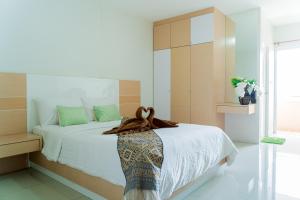 a bedroom with a bed with white sheets and a window at The Infinity Suite Chiangrai in Chiang Rai