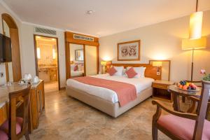 a hotel room with a large bed and a desk at Jolie Ville Hotel & Spa Kings Island Luxor in Luxor