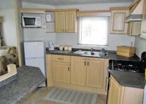 a kitchen with wooden cabinets and a white refrigerator at Rowanbank Caravan Park in Beckfoot