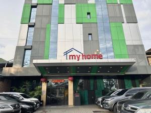 un edificio de mi casa con coches aparcados delante de él en My Home Hotel Pontianak, en Pontianak