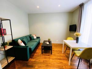 a living room with a green couch and a table at Les Appartements du Grand Hôtel Clichy Paris in Clichy