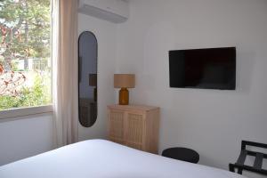 a bedroom with a bed and a tv and a window at Hôtel La Garrigue & Bar Piscine in Venasque